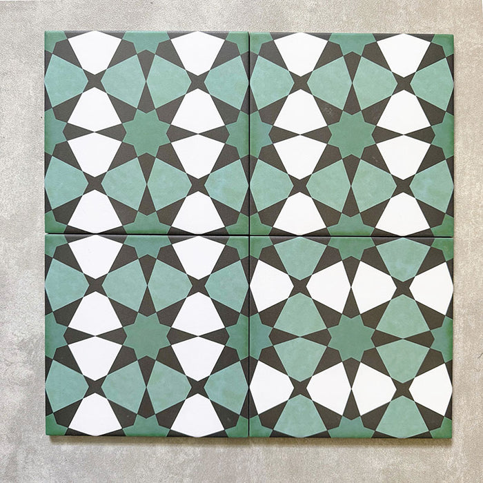 Four Agadir Verde Moroccan-style 20x20cm porcelain tiles laid together, forming a continuous geometric star pattern in soft green, white and charcoal tones.