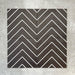 Four Almeria Jilani Black Moroccan-style porcelain wall and floor tiles arranged together to form a continuous white line chevron pattern on a black base, 20x20cm.