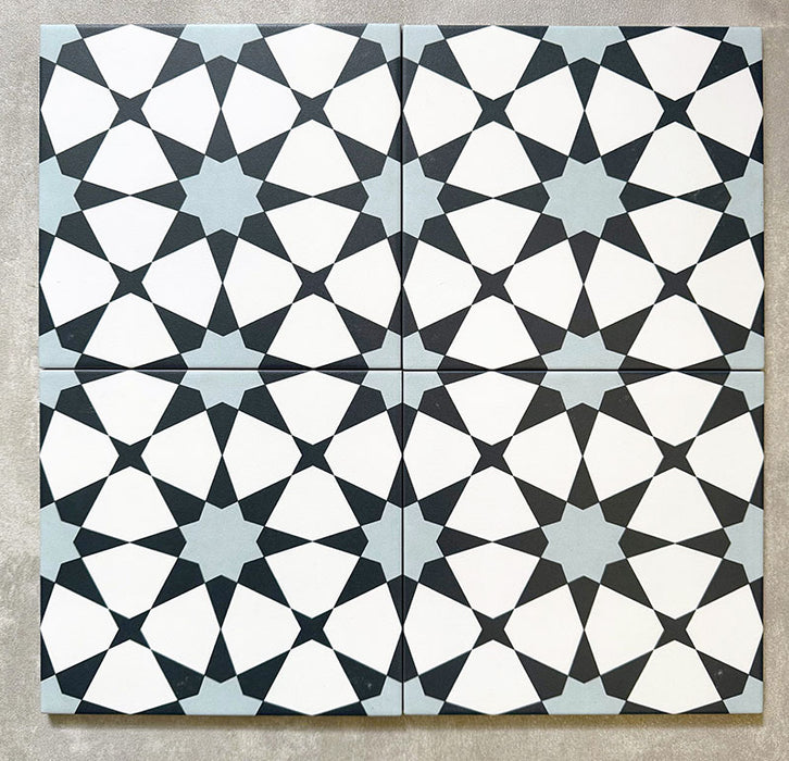 Agadir Azul Blue Moroccan-style 20x20cm porcelain tiles arranged as four tiles, showcasing a repeating geometric star pattern in blue, black and white on a neutral background.