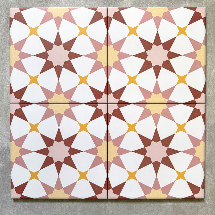 Agadir Springs Moroccan-style 20x20cm porcelain tiles arranged as four tiles, showcasing a repeating geometric star pattern in soft terracotta, blush pink, white and warm yellow tones on a neutral background.