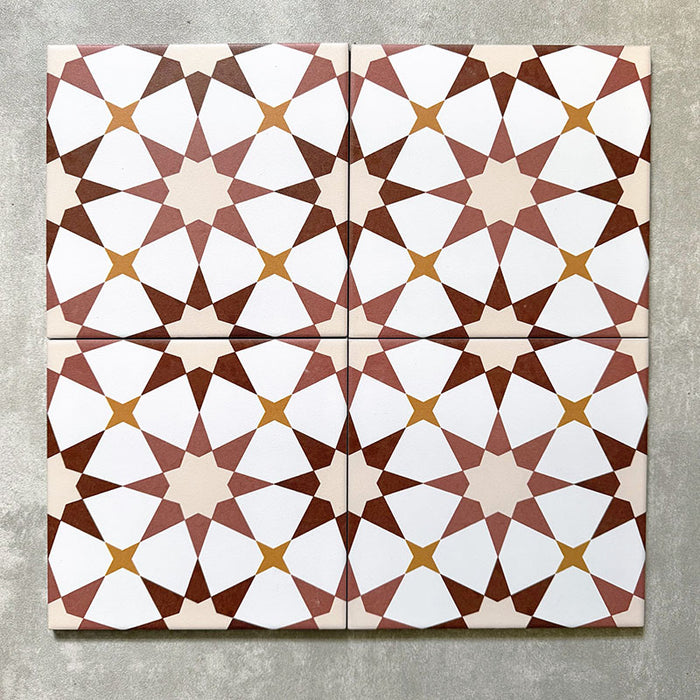 Agadir Cotto Moroccan-style 20x20cm porcelain tiles arranged as four tiles, showcasing a repeating geometric star pattern in warm terracotta, white and soft yellow tones on a neutral background.