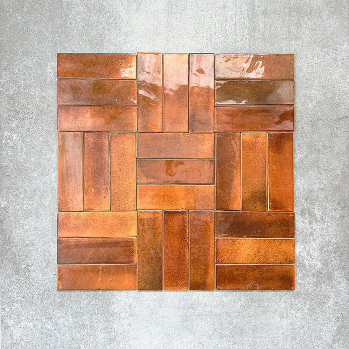 Saigon Amber Brick Wall tiles arranged in a basketweave pattern, featuring Moroccan-style 5.1 × 16.1cm glossy ceramic tiles with rich amber and copper colour variations.