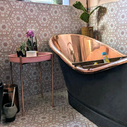 Bathroom featuring Medina Dusty Pink Moroccan-style hexagon porcelain tiles, 18.7 × 21.6 cm, used on walls and floors to create a soft geometric backdrop, styled with a copper bathtub and vintage accessories.