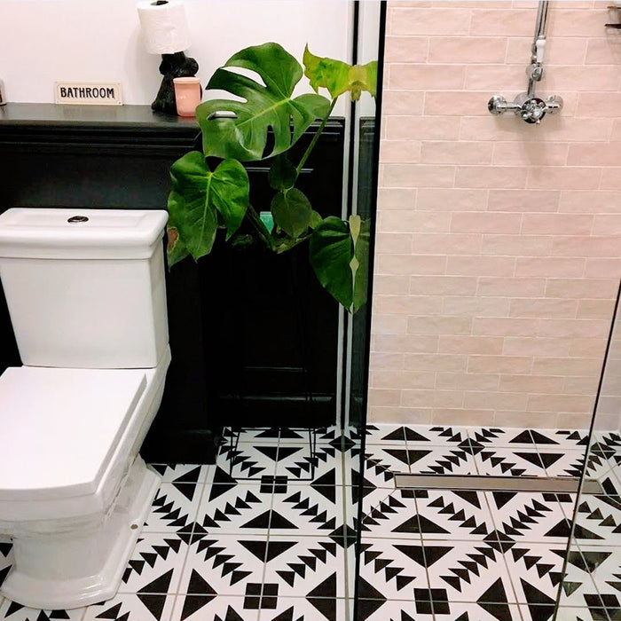 Almeira Azteca Moroccan-style porcelain floor tiles in a contemporary bathroom, showcasing a striking black and white geometric triangle pattern alongside soft pink brick-style wall tiles, 20x20cm.