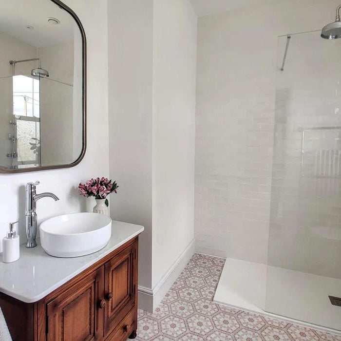 Bathroom interior featuring Medina Dusty Pink Moroccan-style hexagon porcelain floor tiles, 18.7 × 21.6 cm, creating a soft patterned floor paired with a white walk-in shower and wooden vanity unit.