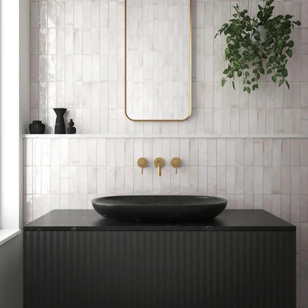 Bathroom wall featuring Saigon White Brick Wall tiles in a Moroccan-inspired style, 5.1 × 16.1cm glossy ceramic tiles in soft white tones, paired with a black vanity, brass fittings, and a minimalist mirror.