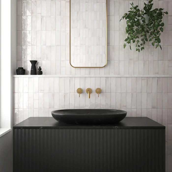 Bathroom wall featuring Saigon White Brick Wall tiles in a Moroccan-inspired style, 5.1 × 16.1cm glossy ceramic tiles in soft white tones, paired with a black vanity, brass fittings, and a minimalist mirror.