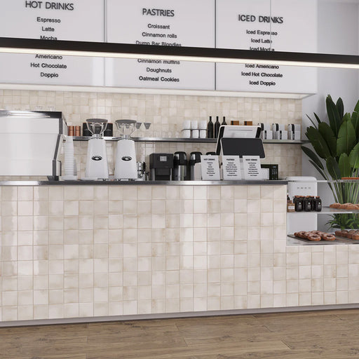 Commercial café counter clad in Saigon White Square Wall tiles in a Moroccan-inspired style, featuring 10 × 10cm glossy ceramic tiles in soft white tones with subtle tonal variation.