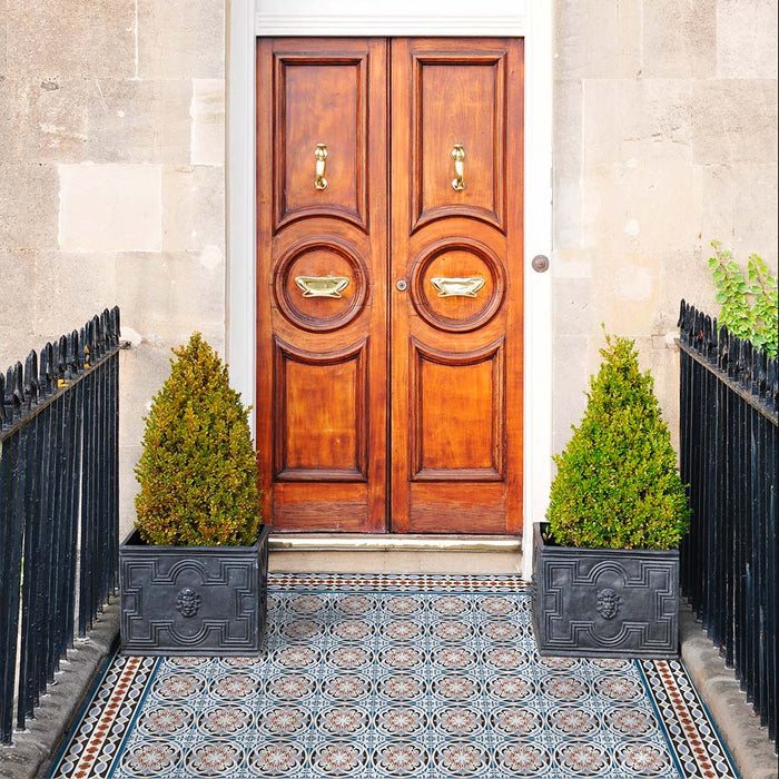 Front doorway featuring Imperial Victorian Blue Mini Border Tiles, 15x15cm porcelain tiles with a classic Victorian-inspired border pattern, framing a decorative tiled entrance beneath a traditional wooden door.