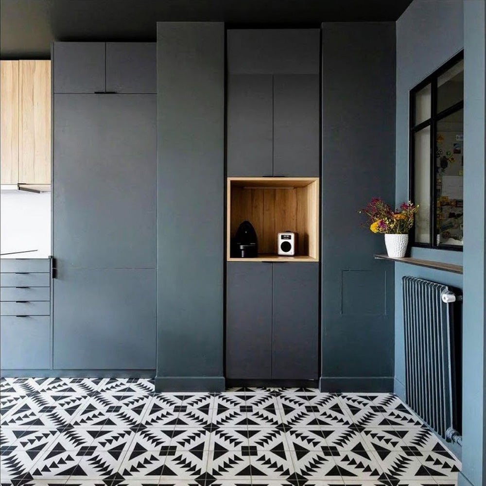 Kitchen floor featuring Almeira Azteca Moroccan-style porcelain tiles in a bold black and white geometric pattern, creating a striking contrast against dark cabinetry, 20x20cm.