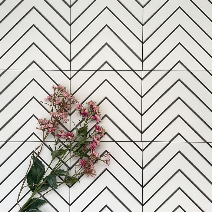 Almeria Jilani White Moroccan-style porcelain wall and floor tiles arranged in a repeating black line chevron pattern on a white base, 20x20cm, styled with decorative flowers.