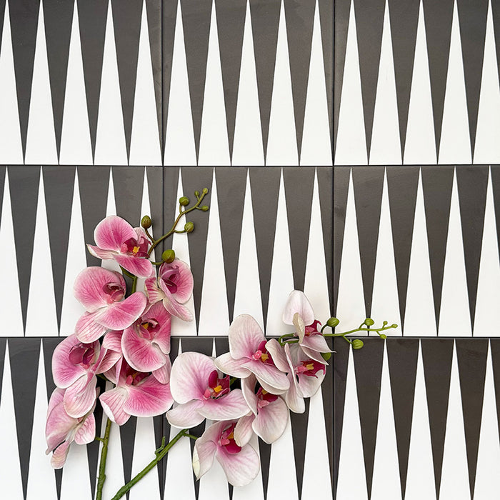 Almeria Backgammon Moroccan-style porcelain wall and floor tiles arranged in a bold black and white geometric pattern, 20x20cm, styled with decorative flowers for a striking display.