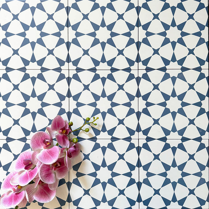Agadir Navy Blue Moroccan-style 20x20cm porcelain floor tiles laid in a repeating geometric star pattern in navy and white, styled with a decorative orchid to highlight the intricate design.