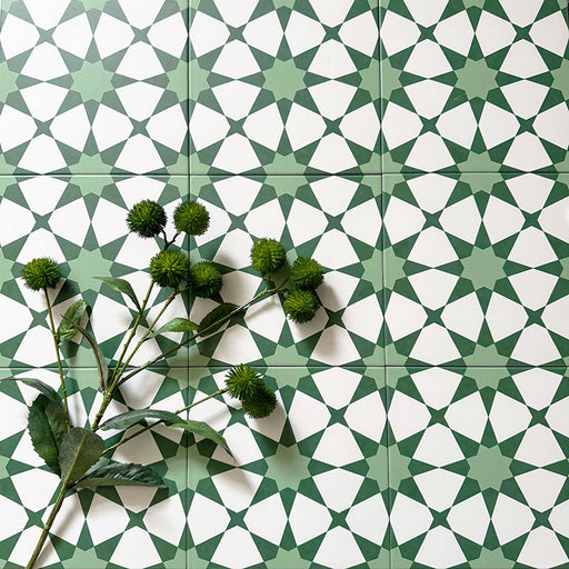 Marketing image featuring Agadir Green Moroccan-style 20x20cm porcelain floor tiles laid in a repeating geometric star pattern in soft green and white, styled with greenery to highlight the fresh, decorative design.