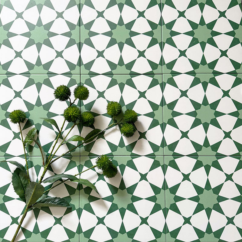 Marketing image featuring Agadir Green Moroccan-style 20x20cm porcelain floor tiles laid in a repeating geometric star pattern in soft green and white, styled with greenery to highlight the fresh, decorative design.