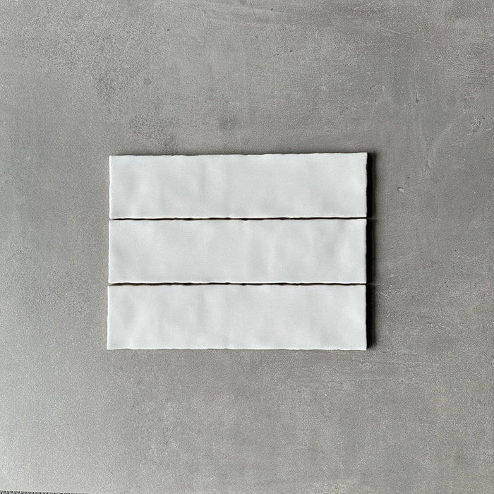 Three Nairobi gloss white handmade-effect tiles shown together, highlighting the subtle tonal variation, lightly textured glazed surface and gently uneven edges of the rustic finish.