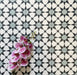 Agadir Azul Blue Moroccan-style 20x20cm porcelain floor tiles laid in a repeating geometric star pattern in blue, black and white, styled with a decorative orchid to highlight the intricate design.