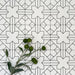 Almeria Palace Moroccan-style porcelain wall and floor tiles arranged in a repeating black line geometric pattern on a white base, 20x20cm, styled with greenery for a decorative display.