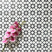 Agadir Black & White Mini Moroccan-style 15x15cm porcelain floor tiles laid in a repeating geometric star pattern, styled with a decorative orchid to highlight the bold black and white design.