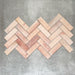 Saigon Rose Pink Brick Wall tiles laid in a herringbone pattern, showcasing Moroccan-style 5.1 × 16.1cm glossy ceramic tiles in soft blush and rose tones with natural colour variation.