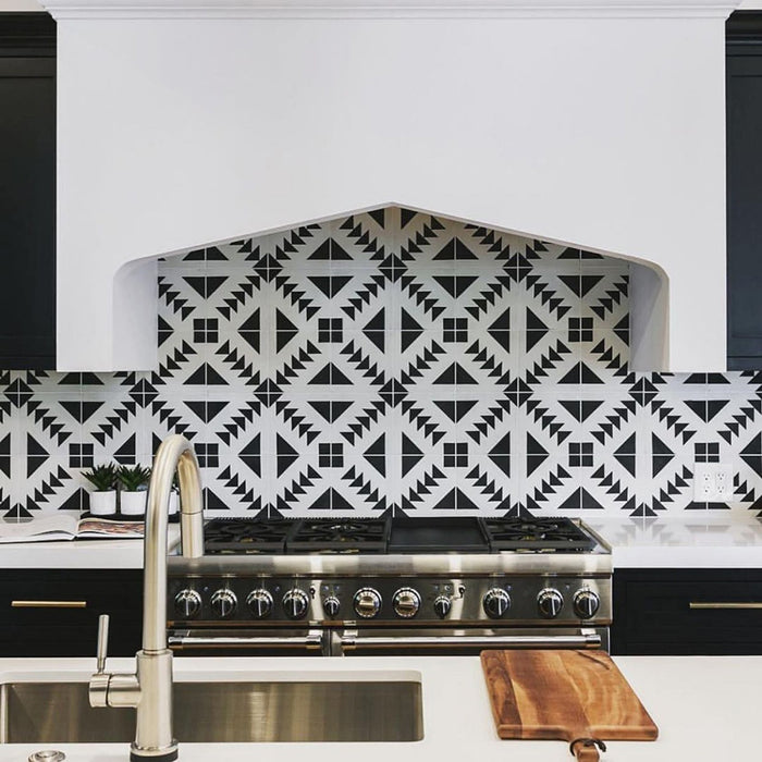 Almeira Azteca Moroccan-style porcelain tiles used as a striking kitchen splashback, featuring a bold black and white geometric triangle pattern behind a cooker, 20x20cm.