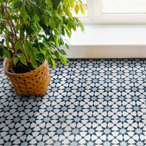 Living space featuring Agadir Azul Blue Moroccan-style 20x20cm porcelain floor tiles, showcasing a geometric star pattern in blue and white, styled with natural light and a potted plant for a fresh, modern look.