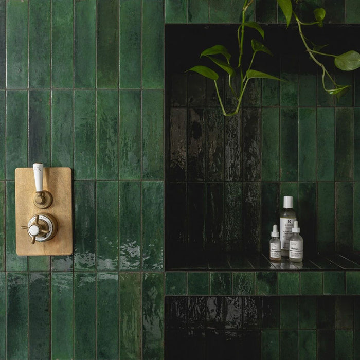 Gloss moss green Nairobi handmade-effect tiles shown in a shower setting, with light reflecting across the textured glazed surface and accenting the depth of colour and natural variation.