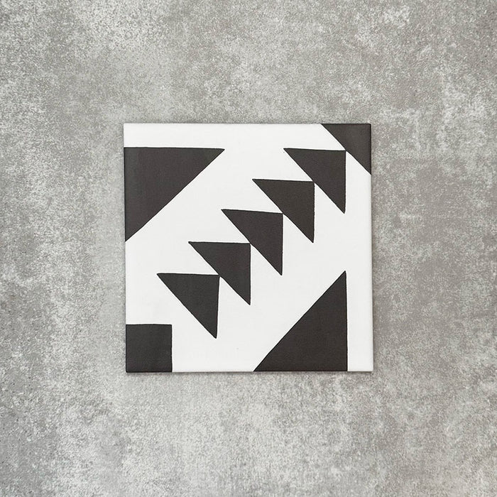 Single Almeira Azteca Moroccan-style porcelain tile featuring a bold black and white geometric triangle pattern, shown individually on a neutral background, 20x20cm.