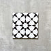 Agadir Black & White Moroccan-style 20x20cm porcelain tile featuring a bold geometric star pattern in black and white, shown as a single tile on a neutral background.