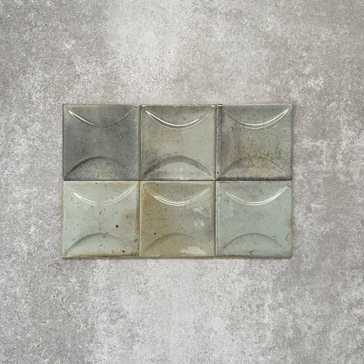 Close-up of Saigon Celadon Green Decor Square Wall tiles, featuring Moroccan-style 10 × 10cm glossy ceramic tiles in soft green and blue-grey tones with a curved decorative relief pattern.