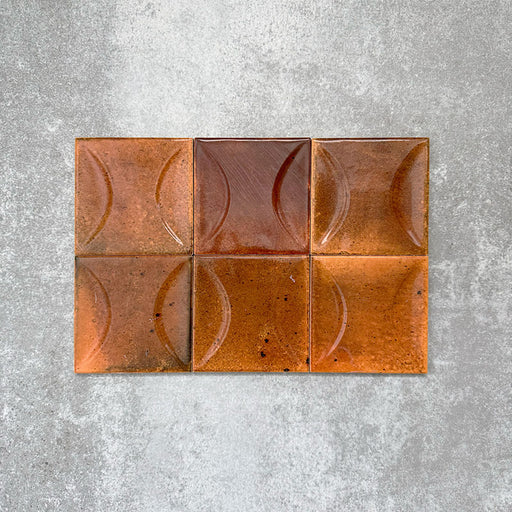 Close-up of Saigon Amber Decor Square Wall tiles, featuring Moroccan-style 10 × 10cm glossy ceramic tiles in warm amber tones with a curved decorative relief pattern.
