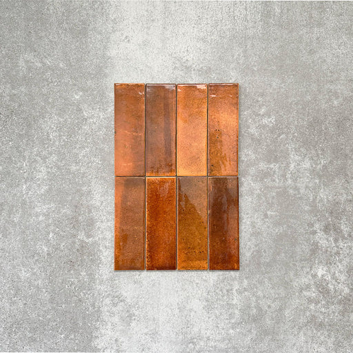 Close-up of Saigon Amber Brick Wall tiles in a Moroccan-style design, 5.1 × 16.1cm glossy ceramic tiles with rich amber and copper tonal variations, shown laid vertically.