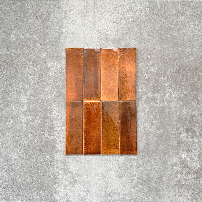 Close-up of Saigon Amber Brick Wall tiles in a Moroccan-style design, 5.1 × 16.1cm glossy ceramic tiles with rich amber and copper tonal variations, shown laid vertically.